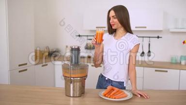 用榨汁机做胡萝卜汁的女人。 用胡萝卜做新鲜果汁。 女孩用胡萝卜准备新鲜果汁。
